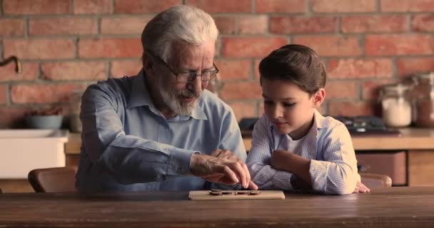 Szczęśliwy stary Dojrzały mężczyzna gra warcaby z małym wnukiem. — Wideo stockowe