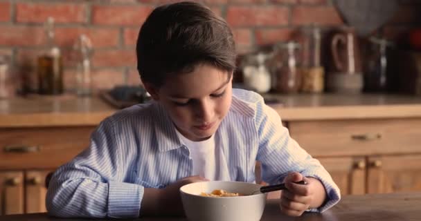 Happy kleine 8s jongen eten cornflakes met melk. — Stockvideo