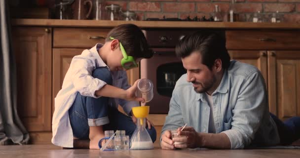 Interesado niño pequeño llevando a cabo entretenidos experimentos químicos con papá. — Vídeo de stock