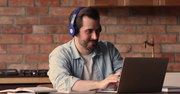 Jovem feliz em fones de ouvido trabalhando no computador em casa. — Vídeo de Stock
