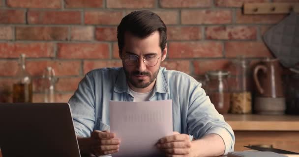Gerente masculino joven enfocado analizando informes de papel, trabajando en la computadora. — Vídeos de Stock