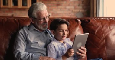 Torunuyla birlikte dijital tablet kullanan 60 'lı yaşlarda bir adam..