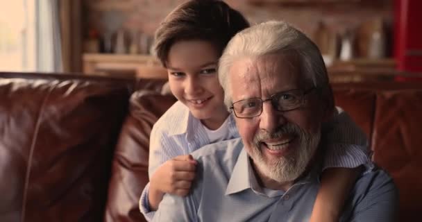 Счастливый маленький школьник обнимает искреннего смеющегося дедушку. — стоковое видео