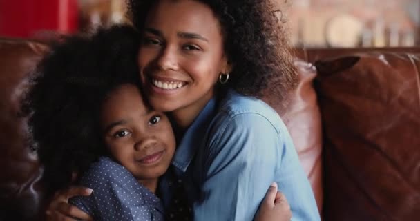 Glücklich liebevoll anhängliche afrikanisch-amerikanische Mutter kuschelt kleine Tochter. — Stockvideo