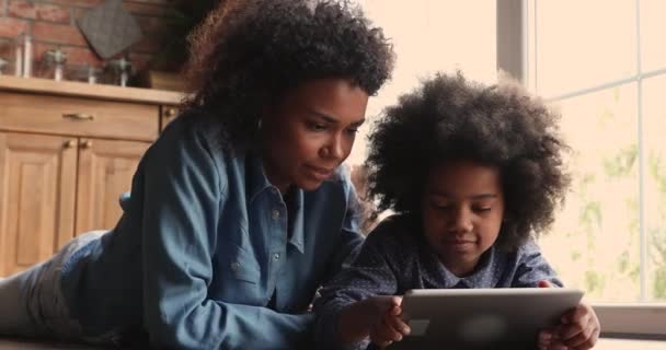 Bela jovem africana etnia mulher usando computador tablet com filha. — Vídeo de Stock