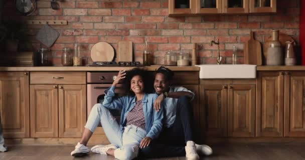 Heureux couple de la famille africaine millénaire assis sur le sol dans la cuisine. — Video