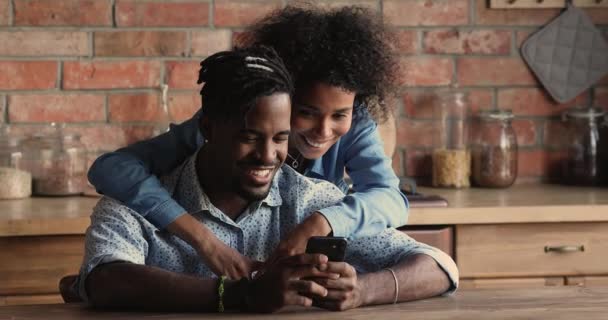 Glad tusenårig afrikansk etnicitet par tittar på roliga mobila video. — Stockvideo