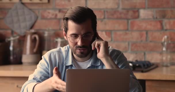 Joven empresario concentrado hablando por teléfono, trabajando en la computadora. — Vídeo de stock