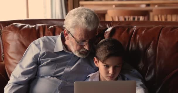 Glücklicher alter Großvater mit kleinem Enkel am Computer. — Stockvideo