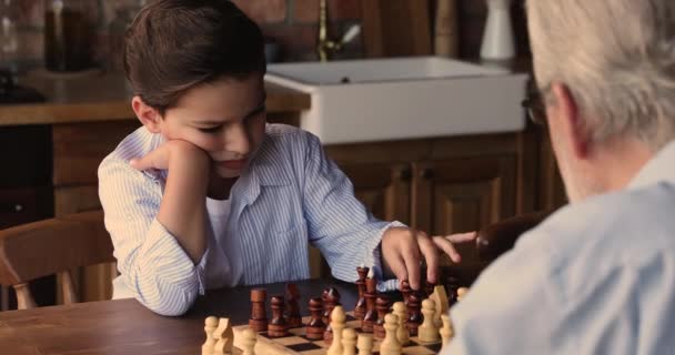 Petit garçon concentré jouant aux échecs avec son grand-père. — Video