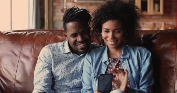 Glad bindning tusenåriga afrikanska amerikanska par med hjälp av smartphone. — Stockvideo