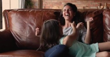 Kız ve anne kanepede dinlenirken birbirlerini gıdıklıyorlar.