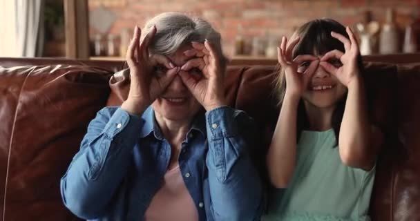 奶奶的小孙女用手指做双目形状 — 图库视频影像