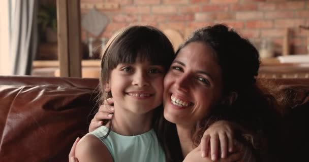 Мама и дочь обнимаются, сидя дома на диване — стоковое видео