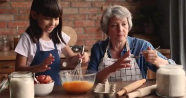 60 'lı yaşlarda yaşlı bir kadın küçük torununa yemek yapmayı öğretiyor.