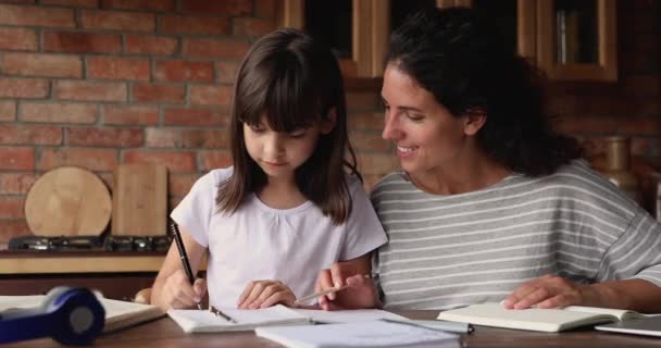 Opiekuńcza matka pomaga małej córce w odrabianiu lekcji — Wideo stockowe