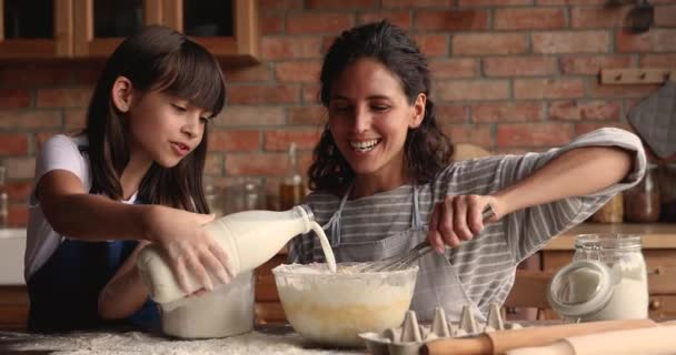 Joven mujer enseñar poco hija cocinar en cocina — Vídeos de Stock