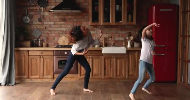 Filhinha sua mãe dançando na cozinha moderna acolhedora — Vídeo de Stock