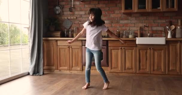 Liten flicka dansar ensam i modernt mysigt kök — Stockvideo