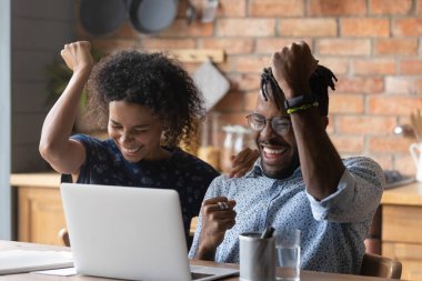 Yakın çekim heyecanlı Afrikalı Amerikalı çift başarıyı kutluyor, dizüstü bilgisayar kullanarak