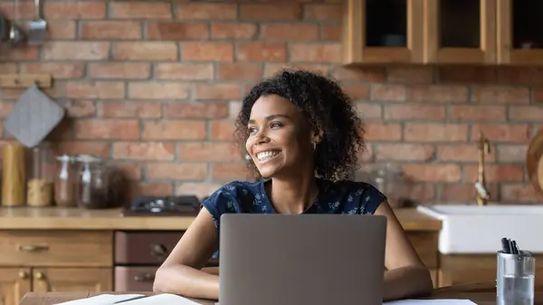 Close-up glimlachen dromerig Afrikaans amerikaanse vrouw afgeleid van laptop — Stockfoto