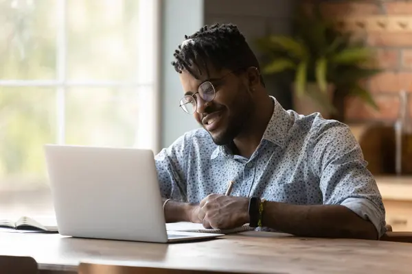 Close up African American man using laptop, taking notes — Stock Photo, Image