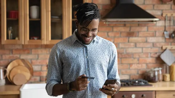 Närbild leende afroamerikansk man betalar kreditkort på nätet — Stockfoto