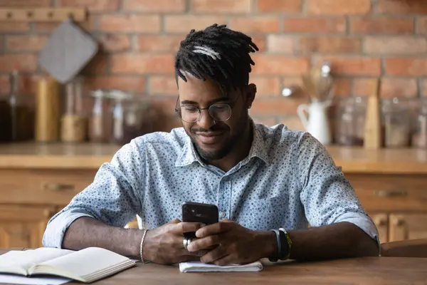 Närbild nöjd afroamerikansk man med hjälp av telefon, bläddra appar — Stockfoto