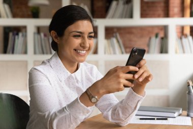 Gülümseyen Hintli kadın video konuşmasında cep telefonu kullanıyor.