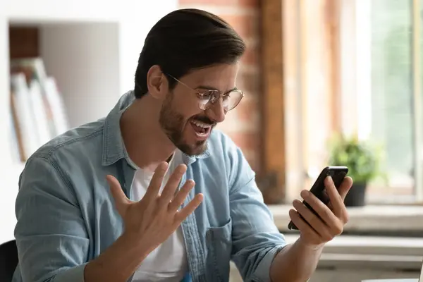 Uomo eccitato guardare lo schermo dello smartphone trionfo con buone notizie — Foto Stock