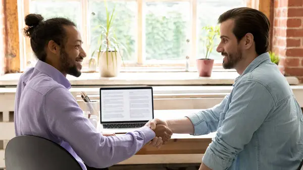 Sonrientes hombres de negocios multirraciales apretón de manos en la reunión en el cargo — Foto de Stock