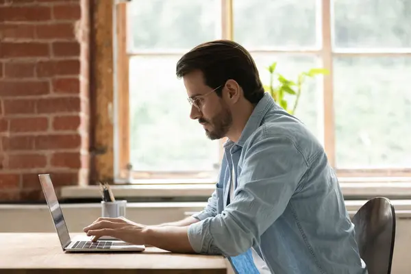 Fokuseret mandlig medarbejder arbejde på laptop i kontoret - Stock-foto