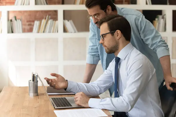 Los colegas serios masculinos trabajan en la computadora en la oficina — Foto de Stock