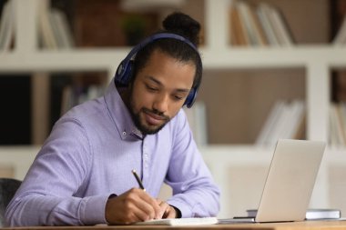 Kulaklıklı Afrikalı Amerikalı adam internette çalışıyor.