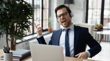 Mutlu iş adamı ofiste kulaklıkla müzik dinler.