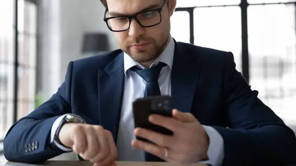 Närbild av ung affärsman använda smartphone och handklocka — Stockfoto