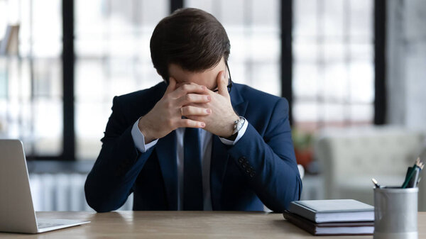Unhappy businessman sit at desk distressed with business failure