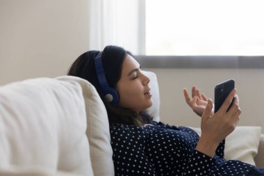 Huzurlu genç Vietnamlı kadın rahatla ve kulaklıkla rahatlatıcı melodinin tadını çıkar.