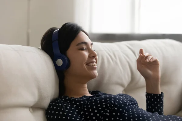 Jonge Aziatische vrouw melomane ontspannen door liedjes in moderne oortelefoons — Stockfoto