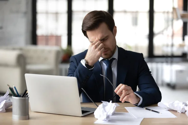 Empresário cansado sofre de dor de cabeça trabalhando no laptop — Fotografia de Stock