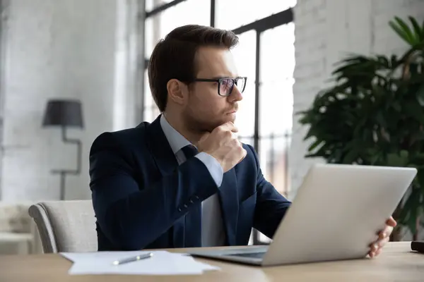 Pensive businessman práce na notebooku v kanceláři myšlení — Stock fotografie