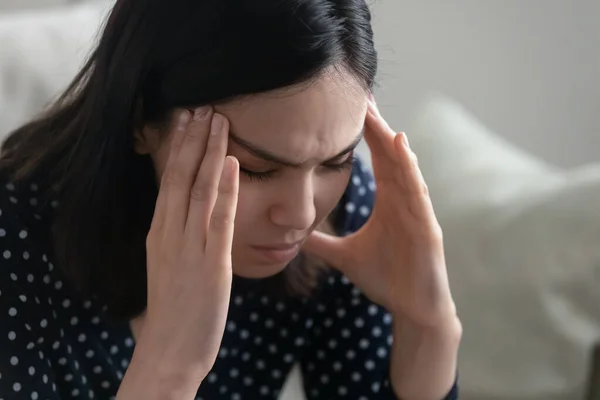 Jong aziatische vrouw zitten alleen wrijven tempels met hoofdpijn migraine — Stockfoto
