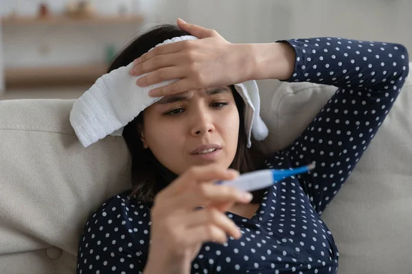 Zieke aziatische vrouw voelt slecht vasthouden natte handdoek op het voorhoofd — Stockfoto