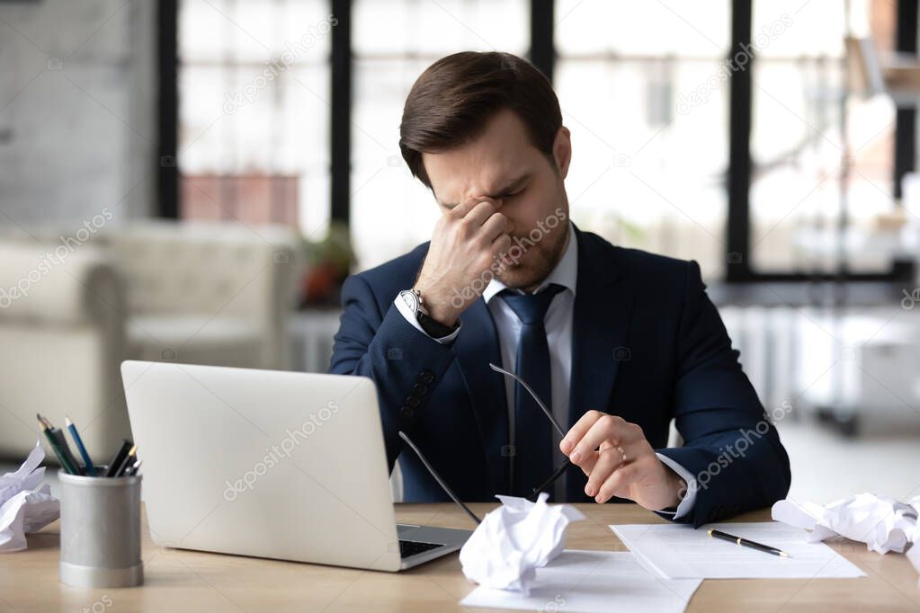 Tired businessman suffer from headache working on laptop