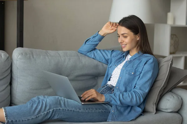 Smiling teenage female rest on sofa with laptop on knees — Stock Photo, Image