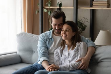 Genç koca kanepeye otur ve sevgili karısını kucakla.