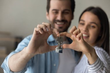 Mutlu çift yeni evden anahtar göstermek için parmak kalp yapar.