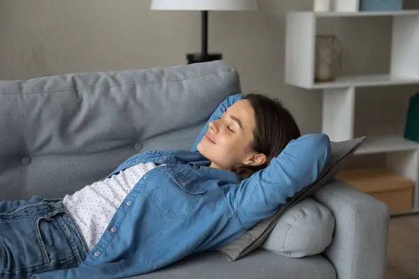 Mujer adolescente acostada en un sofá con los ojos cerrados disfrutando de la comodidad — Foto de Stock