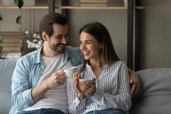 Sorridente giovane coppia innamorata seduta sul divano a bere tè — Foto Stock