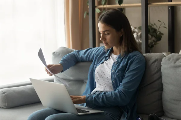 Ung kvinna läsa papper brev kontrollera information på nätet med bärbar dator — Stockfoto